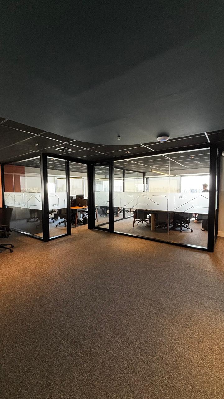 Vista das divisórias de vidro com perfis pretos em ambiente corporativo