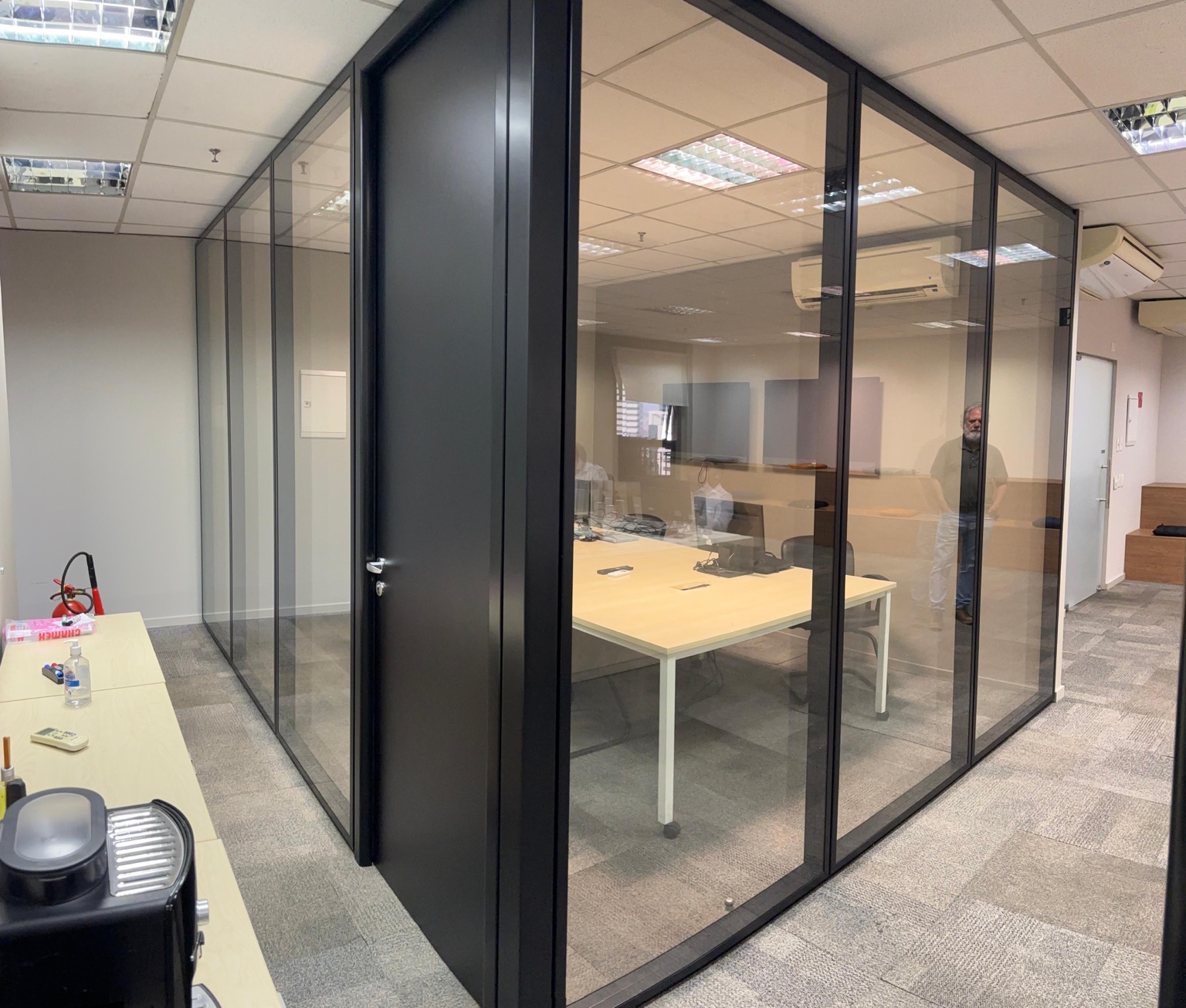 Escritório com divisórias de vidro e porta preta em projeto Formi