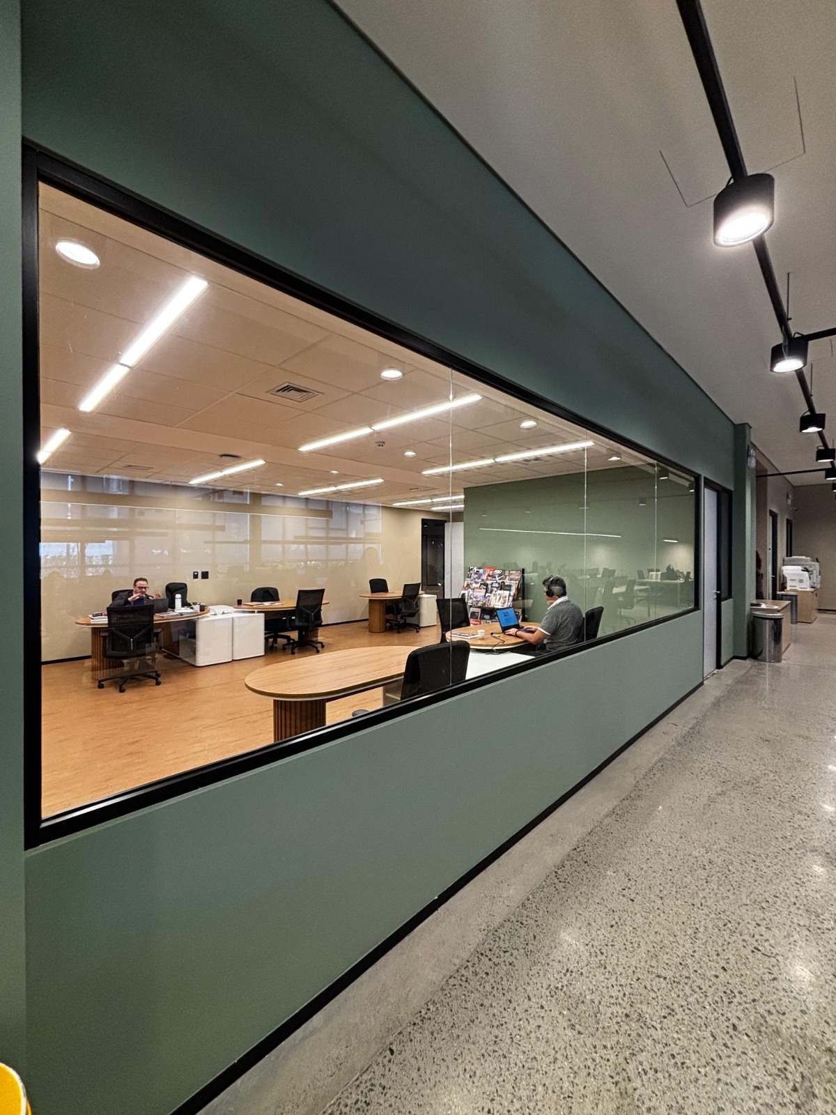 Escritório com ampla divisória de vidro e acabamento verde em projeto Formi