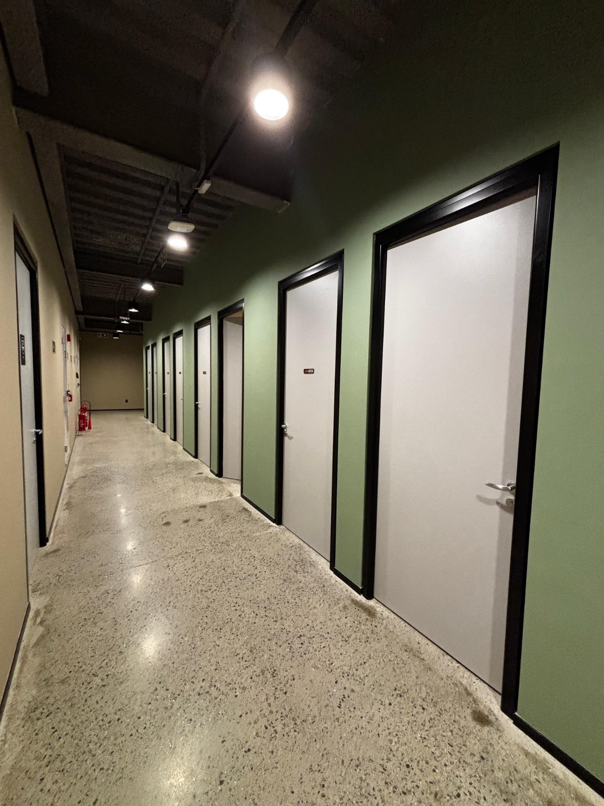 Corredor com portas claras e perfis pretos em projeto Formi