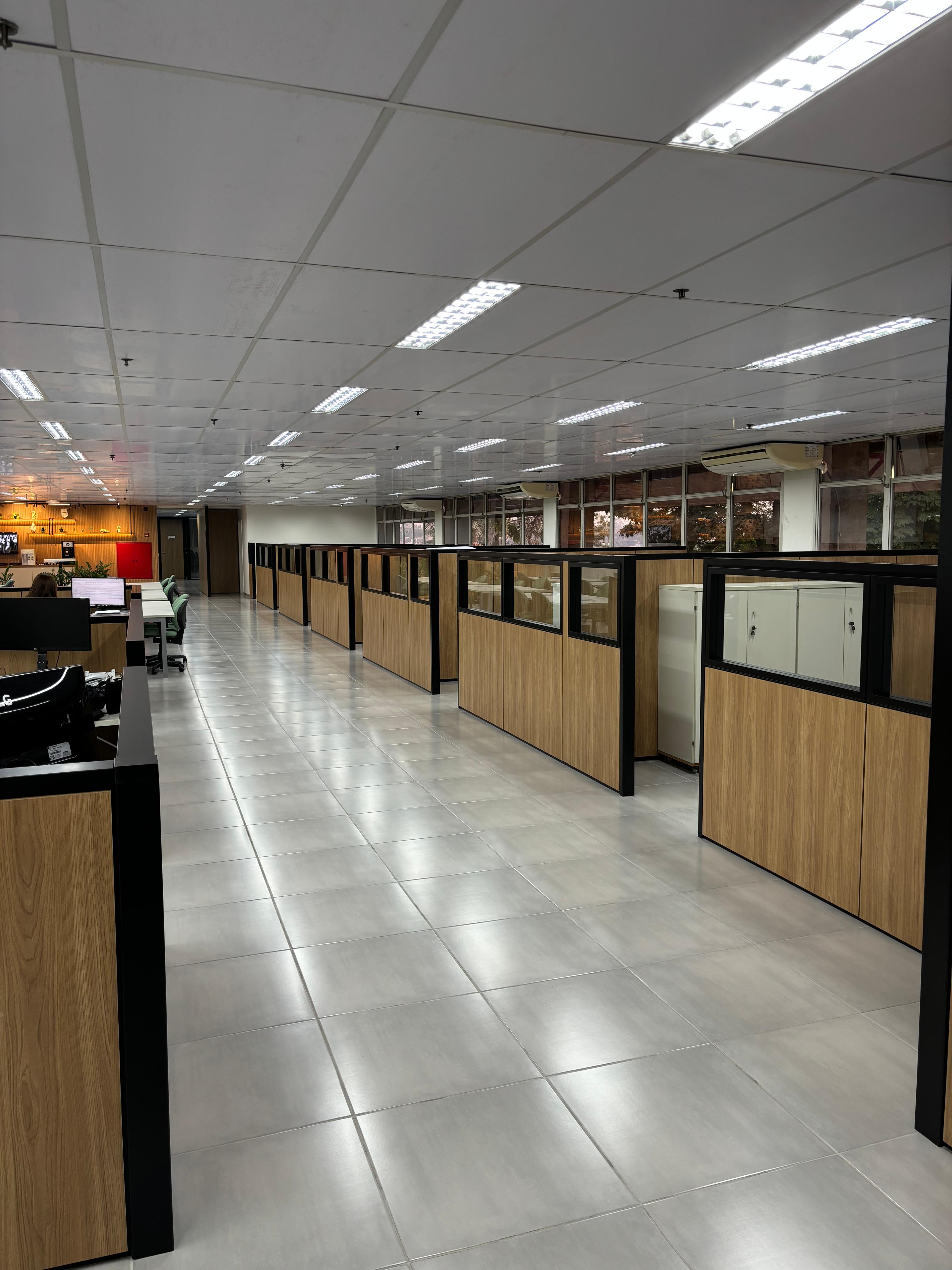 Vista geral de escritório com divisórias amadeiradas e perfis pretos em projeto Formi